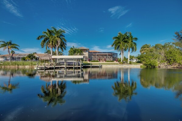 A waterfront property with a dock, palm trees, and a clear blue sky.