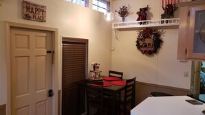 A cozy dining area with a table and chairs, a decorative wreath on the wall, and a sign above the door. - Year Round Access in town Bungalow, Hot Tub, Fire Pit and Extra Parking      (Maggie Valley)