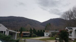 A residential area with houses, a driveway, and a mountain backdrop. - Year Round Access in town Bungalow, Hot Tub, Fire Pit and Extra Parking      (Maggie Valley)