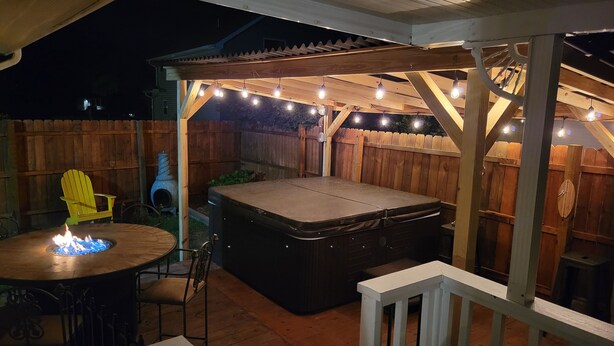 An outdoor patio with a hot tub, a wooden deck, and string lights. - Year Round Access in town Bungalow, Hot Tub, Fire Pit and Extra Parking      (Maggie Valley)