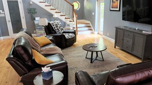 A living room with leather sofas, a coffee table, a TV, and a staircase. - Ponte Vedra Wilderness Oasis minutes from TPC and the beach (Ponte Vedra Beach)
