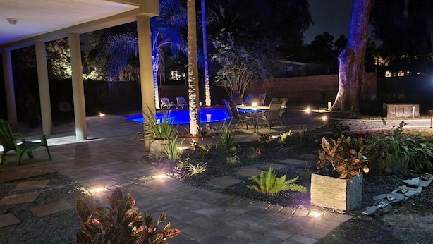 An outdoor patio area with a swimming pool, seating, and well-lit plants. - Ponte Vedra Wilderness Oasis minutes from TPC and the beach (Ponte Vedra Beach)