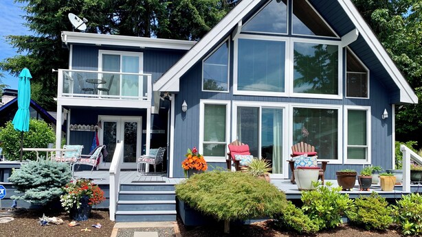 A two-story house with a balcony, large windows, and a well-maintained garden. - Hood Canal "Seaside Chalet". Beautifully updated and decorated.  Lovely setting! (Belfair)
