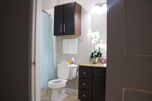 A bathroom with a white toilet, dark cabinets, a towel rack, and a mirror.
