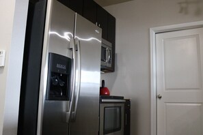 A kitchen with a stainless steel refrigerator, a microwave, and a small oven.