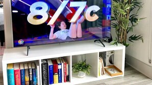 Ein Flachbildfernseher auf einer weißen Unterhaltungsanlage mit einem Bücherregal darunter.