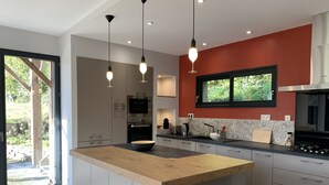 Uma cozinha moderna com ilha central, eletrodomésticos de aço inoxidável e uma parede com detalhes em vermelho.