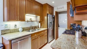 A modern kitchen with wooden cabinets, stainless steel appliances, and a granite countertop.