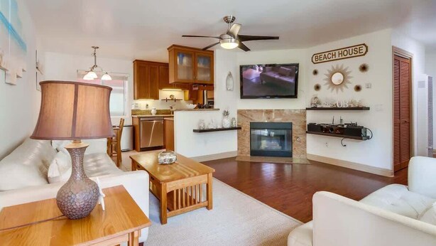 A living room with a fireplace, a television, and a ceiling fan.