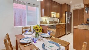 A kitchen with wooden cabinets, a refrigerator, and a dining table set with plates and glasses.