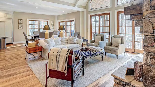 A spacious living room with a fireplace, large windows, and a cozy seating area.