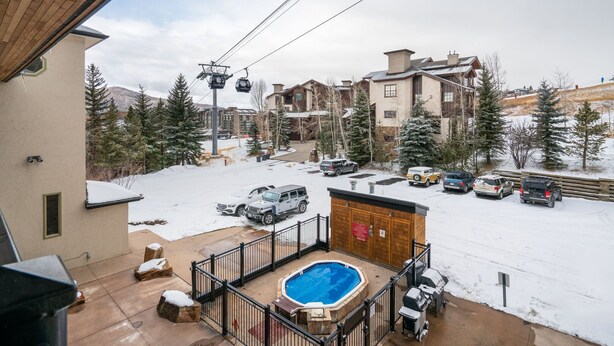 Et boligområde med swimmingpool, en overdækket terrasse og udsigt til en skilift og bygninger i baggrunden.