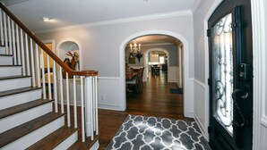 A staircase leading to a dining area with a chandelier, wooden railing, and a patterned rug. - Remodeled Aggieland Historic Home/Gameday Retreat (College Station)
