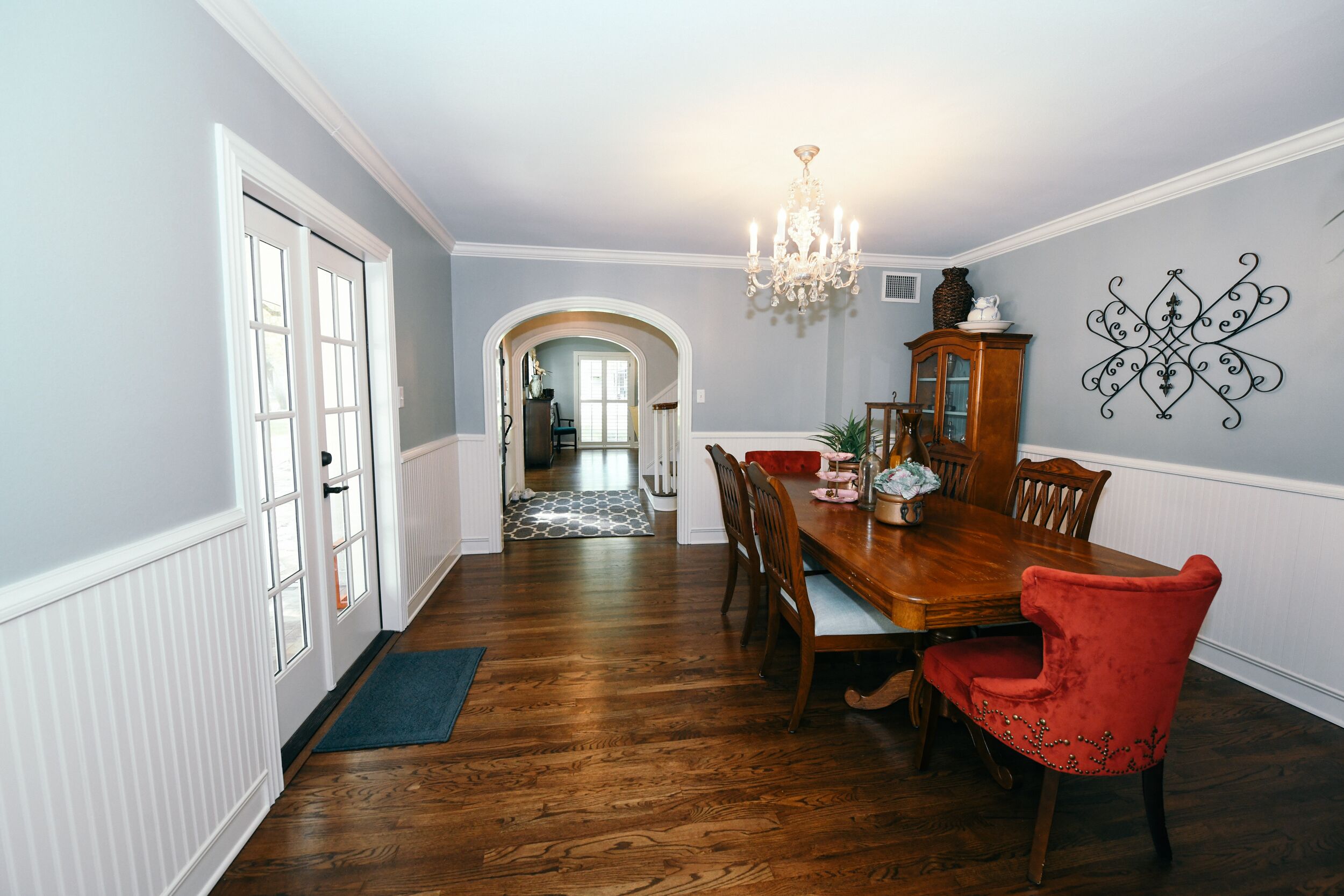 A dining room with a wooden table, red upholstered chairs, and a chandelier.