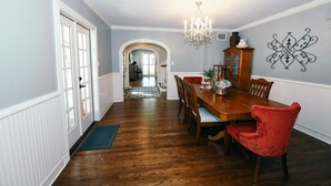 A dining room with a wooden table, red upholstered chairs, and a chandelier. - Remodeled Aggieland Historic Home/Gameday Retreat (College Station)