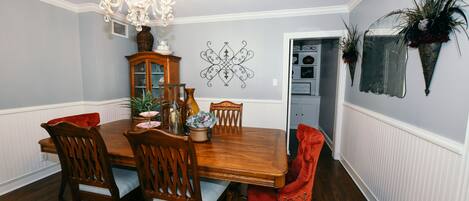 A dining room with a wooden table, four chairs, a chandelier, and decorative wall art.