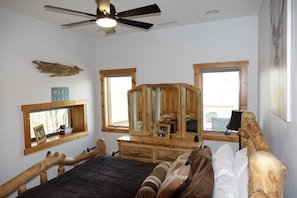 A bedroom with a bed, wooden headboard, a ceiling fan, and two windows. - Whispering Pines Lakehouse - private dock and free zipline and railroad passes (Bryson City)