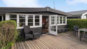A wooden deck with outdoor seating, a covered patio area, and a view of the interior through open doors. - Lovely home in Bjert with kitchen (Bjert)