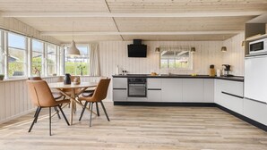 A modern kitchen with wooden paneling, a central island, and a dining area with chairs. - Lovely home in Bjert with kitchen (Bjert)