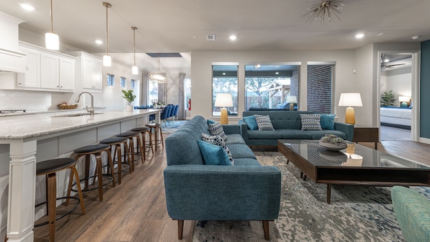 A modern kitchen with white cabinets, a bar area with stools, a large island, and a seating area with sofas and a coffee table. - Walk to Stadium-4 Full Bath, Hot Tub • Mini Golf • Game Room  (Arlington)