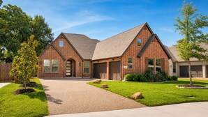 A two-story brick house with a large garage, a covered driveway, and well-maintained landscaping. - Walk to Stadium-4 Full Bath, Hot Tub • Mini Golf • Game Room  (Arlington)