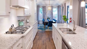 A modern kitchen with white cabinetry, granite countertops, and a central island. - Walk to Stadium-4 Full Bath, Hot Tub • Mini Golf • Game Room  (Arlington)
