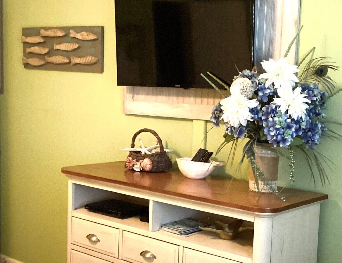 A wooden console table with a decorative basket, a bowl, and a vase with flowers.