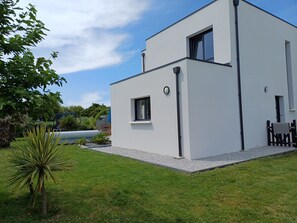 A modern two-story building with a white exterior, a small window, and a door. - 4 * vacation home between La Torche and Pors Carn with swimming pool. (Penmarch)
