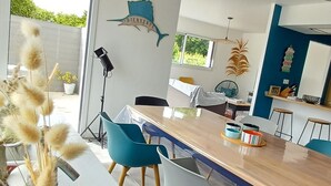 A modern dining area with a wooden table, blue chairs, and a decorative wall piece. - 4 * vacation home between La Torche and Pors Carn with swimming pool. (Penmarch)