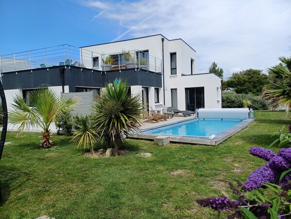 A modern two-story house with a swimming pool, surrounded by a well-maintained lawn and various plants. - 4 * vacation home between La Torche and Pors Carn with swimming pool. (Penmarch)