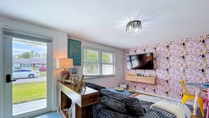 Un salon moderne avec un canapé, un téléviseur fixé au mur et un papier peint à motifs.