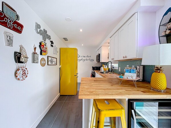 A modern kitchen with white cabinets, a yellow refrigerator, and various coffee-themed decorations on the walls. - Charming, Family Friendly Newly Renovated Duplex on Holmes Beach (Holmes Beach)