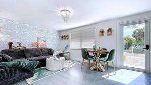 Un salon moderne comprenant un canapé, une table basse et un coin repas avec des chaises.