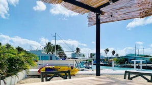 Uma área à beira-mar com espaço de estar coberto, piscina e barcos.