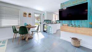 Ett modernt kök med vita skåp, en inbyggd mikrovågsugn och en stor, platt tv-skärm som är monterad på väggen.