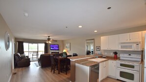 A modern kitchen with a central island, built-in appliances, and a dining area with a TV. - Large, Beautifully Furnished -Sleeps 12,  6 beds -2 kings & 4 queens -BLDG 10 (Osage Beach)