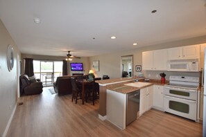 A modern kitchen with a central island, built-in appliances, and a dining area with a TV.