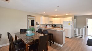 A modern kitchen with white cabinets, a granite countertop, and a built-in island with bar stools. - Large, Beautifully Furnished -Sleeps 12,  6 beds -2 kings & 4 queens -BLDG 10 (Osage Beach)