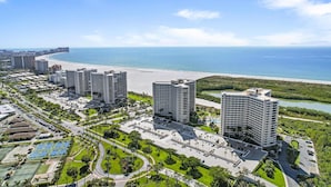 Una zona turistica costiera con edifici alti, una spiaggia e un porto turistico.
