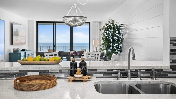 Una cucina moderna con un'isola grande, lavello in acciaio inossidabile e un lampadario.