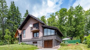 Une maison moderne à deux étages, dotée d’une façade en pierre, de grandes fenêtres et d’un balcon.