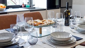 Une table à manger dressée avec des assiettes, des bols, des verres et une bouteille de vin.