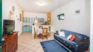Espai vital compacte amb zona de dinar, petita cuina i sofà.