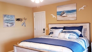 A bedroom with a bed, a nightstand, and wall art including a seascape painting and a sign that reads "LAKEFLY". - Eufaula Lakefront House In Quiet Neighborhood w/ Private Dock & Game room (Canadian)