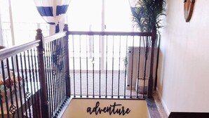 A staircase with a handrail, a sign reading "adventure," and a view of the outside through a window with blue and white curtains. - Eufaula Lakefront House In Quiet Neighborhood w/ Private Dock & Game room (Canadian)