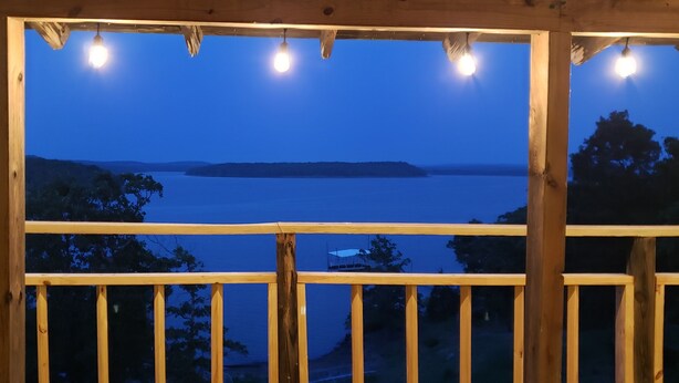 A wooden deck with a view of a calm body of water and distant landforms. - Eufaula Lakefront House In Quiet Neighborhood w/ Private Dock & Game room (Canadian)
