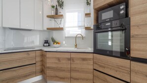 Une cuisine moderne avec des meubles en bois, un four encastré et une machine à café.