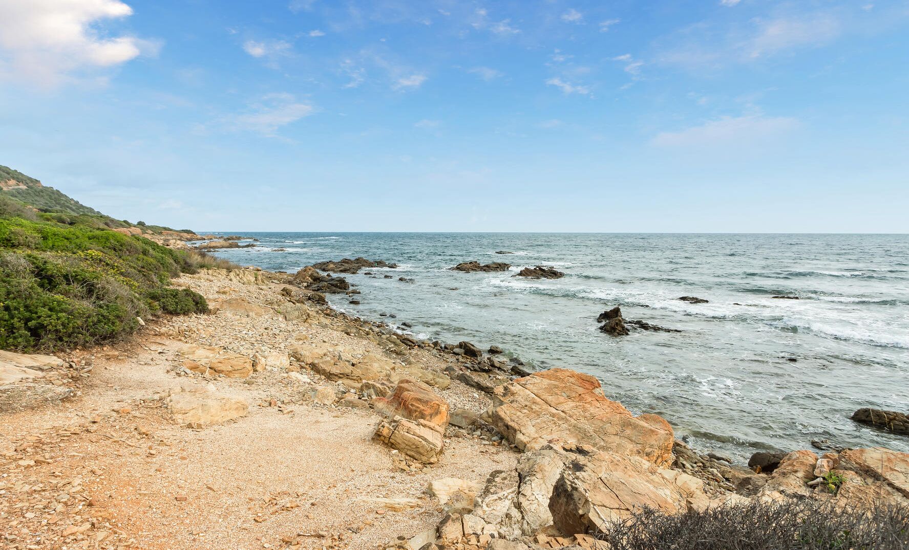 Un paisaje costero con terreno rocoso y el mar.