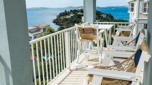 Un balcon avec des meubles blancs et une vue sur la mer.