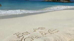 Une plage où l’on peut voir des empreintes de pas dans le sable, et d’où l’on a une vue dégagée sur l’océan et les îles lointaines.